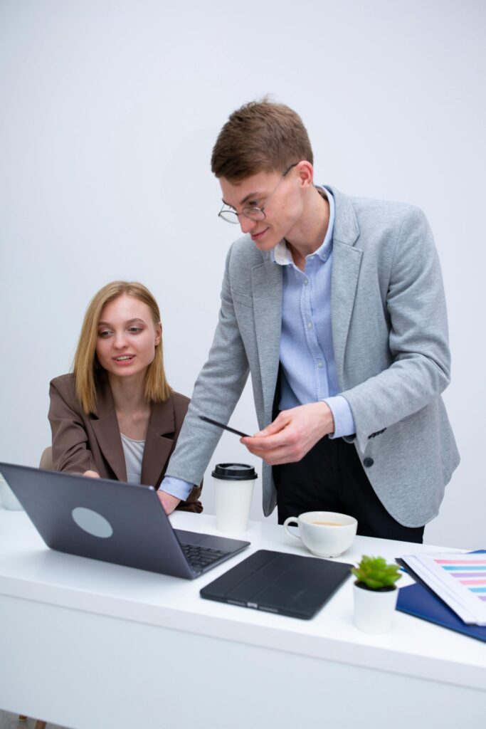 pexels photo 6930538 6930538 Two business professionals collaborating at a desk with a laptop, engaged in discussion.